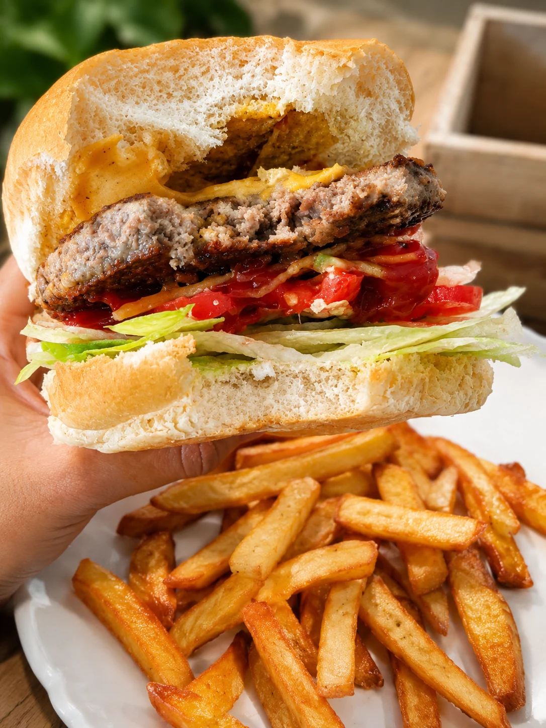 A burger with lettuce, tomato, bacon and a plate of chips